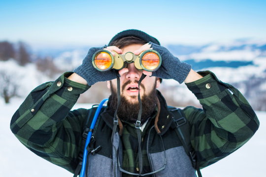 Man using binoculars on snow covered mountain