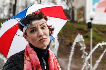 Emotional girl with colorful umbrella on her head in the park