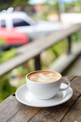 Coffee cuo Latte art on grunge wooden table outdoor