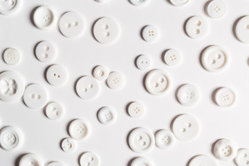 Scattered white buttons flat lay overhead view on white