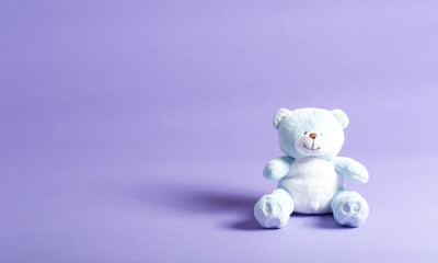 Baby blue child's teddy bear stuffed animal on a purple background