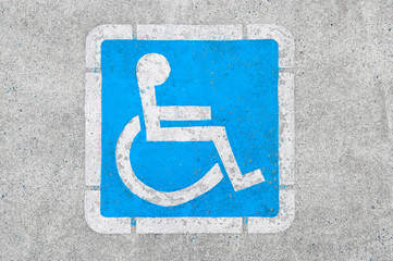 Blue disabled parking sign painted on dark asphalt in Canada in Ucluelet, Canada