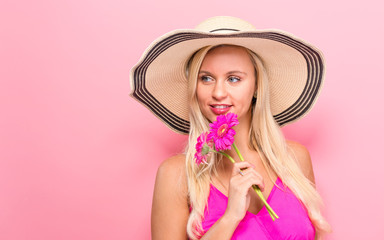 Young woman with flowers on a pink background