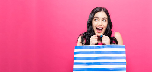 Young woman holding a shopping bag on a pink background