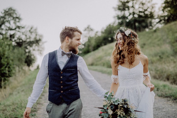 Beautiful bride and groom in green nature, holding hands.