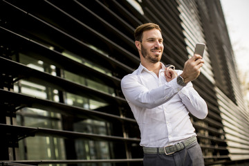 Happy smiling urban businessman using smart phone and taking selfie outside