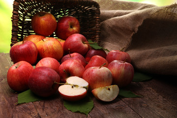 Ripe red apples with leaves on wooden background