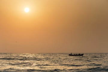 Fishermen silhouettes on boat, at sunrise