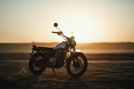  old custom beautiful cafe racer motorcycle in the desert at sunset or sunrise 