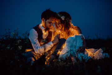 Beautiful bride and groom on a meadow at night.