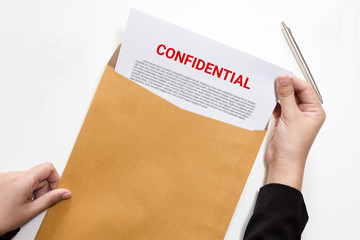Woman hands holding and looking at confidential document in envelope - business concept.