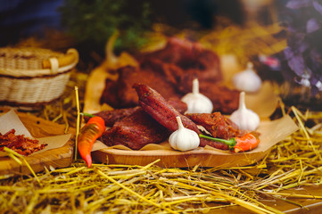 jerky with garlic and pepper composition on straw and wood, rustic style