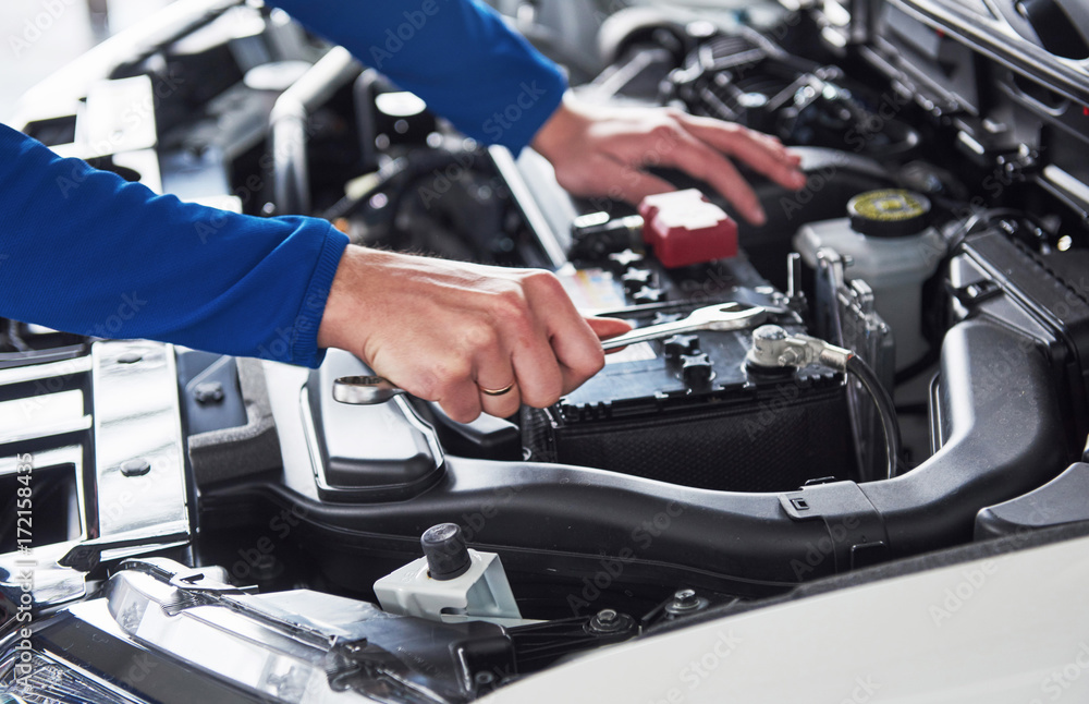 Wall mural hands of car mechanic with wrench in garage