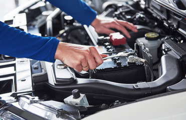 Fototapeta na wymiar Hands of car mechanic with wrench in garage
