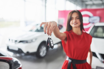 Smiling car salesman handing over your new car keys, dealership and sales concept. Happy girl the...