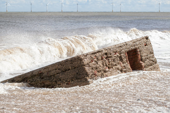 Rising Sea Level. Wave Flooding Beach And Engulfing Historical WW2 Military Defense Structure.