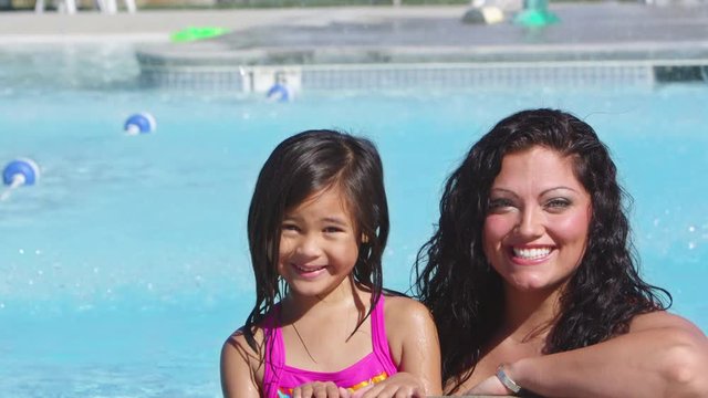 Pan down to mother and daughter at the pool
