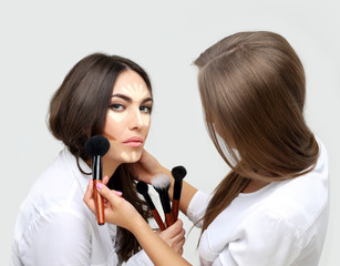 Applying Make-up. Woman with a brush for make-up.Female friends putting makeup 