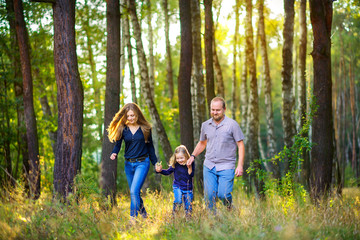 happy family walks in a beautiful evening park, holding hands and running around