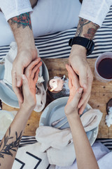 Couple on romantic date in chic, bohemian, provence style picnic, warm their hands next to candle light, concept love, dreaminess, corny and amorous