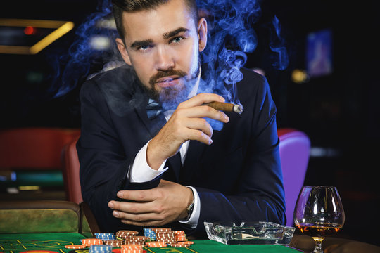 Rich handsome man smoking cigar in the casino
