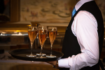 Male waiter welcomes guests with sparkling wine