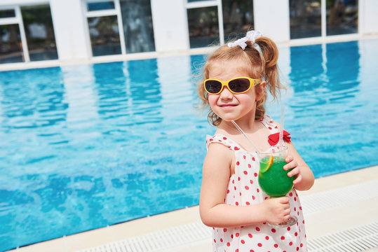 Cute little blonde at the pool and holding a child's cocktail