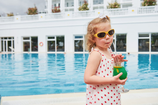 Cute little blonde at the pool and holding a child's cocktail