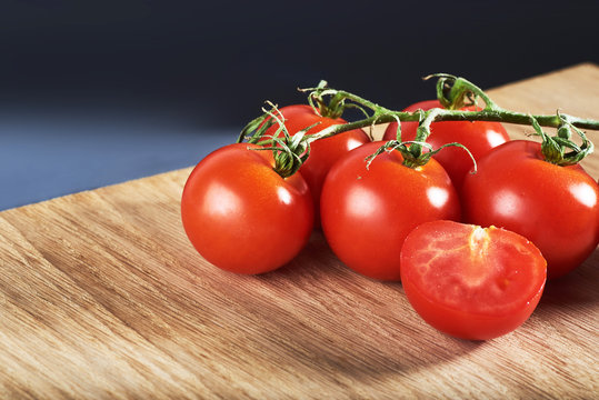 Branch of red cherry tomatoes organic wooden background.