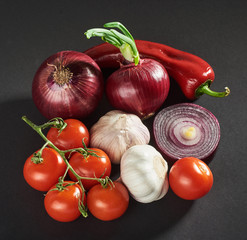 onion and garlic and hot peppers and tomatoes isolated on a black background.