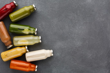 Assortment of detox smoothies in glass bottles on gray background.