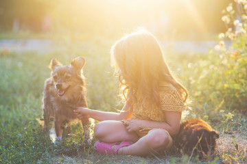 little girl is playing with a little dog at sunset