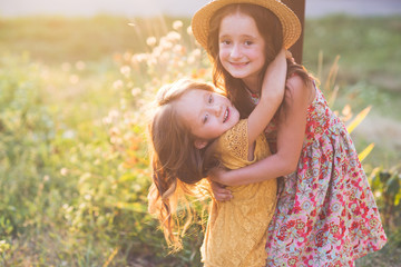 two little girls in beautiful cocktail dresses walking in an autumn park. the concept of humane...