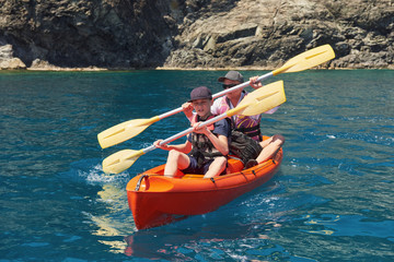 Boat kayaking near cliffs on a sunny day. Kayaking in a quiet bay. Amazing views. Travel, sports concept. Lifestyle. A happy family.