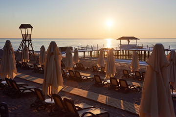 Scenic view of private sandy beach with sun beds and parasokamy the sea and mountains. Resort.