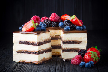 Delicious cake with fruit and berries on black wooden table