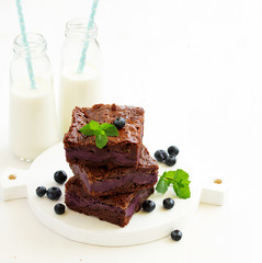 Chocolate brownies with blueberries and cream filling. Dark background.