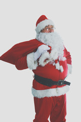 Real Santa Claus carrying big bag full of gifts, isolated on white background