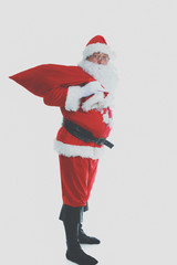 Real Santa Claus carrying big bag full of gifts, isolated on white background