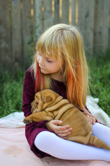 Little blond girl with cute puppy on her hands. Shar pei dog - little pet