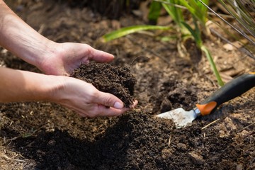 Woman pouring soil in garden