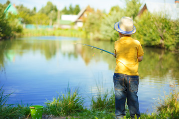 Little boy is engaged in fishing in a pond. Child with a dairy in his hands.