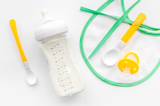 bottle with breastmilk and infant formula powdered healthy food, toys and bib on white background top view