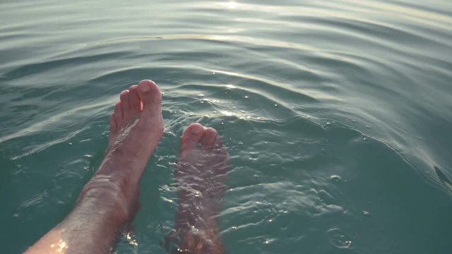 Bare male feet in cool blue swimming pool water