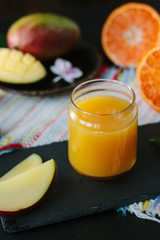 Mango and orange detox juice over black slate board.