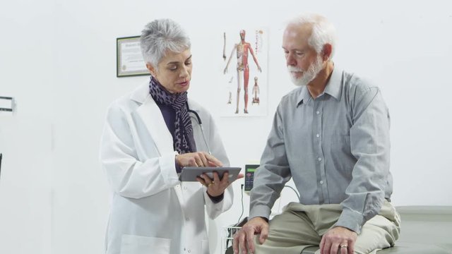 Doctor using tablet to talk to elderly male patient