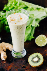 Vegan kiwi and ginger smothie on black rustic surface.