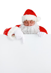 Happy Santa Claus looking out from behind the blank sign isolated on white background