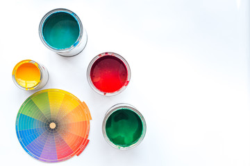 Choosing color for painting. Palette and paints in tin banks on white background top view copyspace