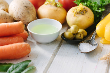 Vegetables, olives and spices over white wooden table.